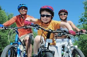 משפחה רוכבת אל אופניים כשהם חובשים קסדות ומשקפי שמש
