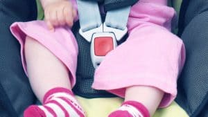 ילדה יושבת במושב בטיחות עם חגורה